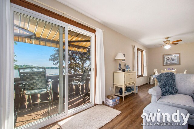living room with dark hardwood / wood-style flooring, ceiling fan, and a water view