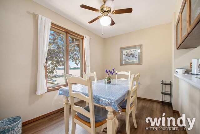 dining space with dark hardwood / wood-style floors, ceiling fan, and a water view