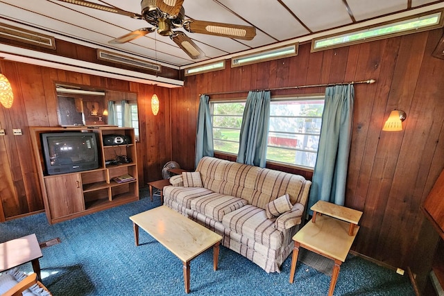 carpeted living room featuring ceiling fan and wood walls