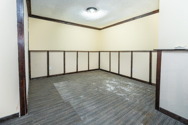 spare room with dark colored carpet and a textured ceiling