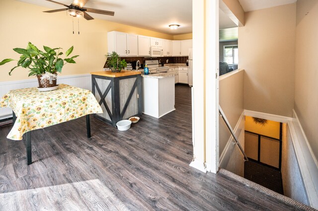 kitchen featuring white cabinetry, wooden counters, dark hardwood / wood-style floors, kitchen peninsula, and white appliances