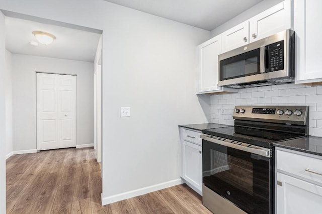 kitchen with backsplash, white cabinetry, stainless steel appliances, and light hardwood / wood-style flooring