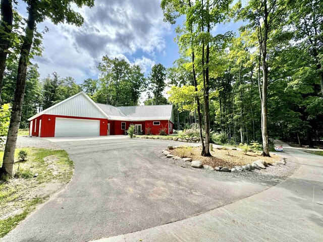 2144 N Jacobson Rd, Suttons Bay, MI 49682 - view of front of property featuring an attached garage, driveway, and view of wooded area