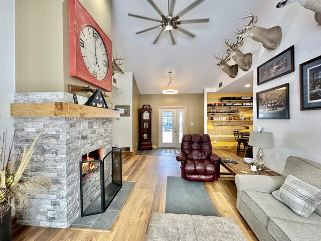 2144 N Jacobson Rd, Suttons Bay, MI 49682 - living area with a stone fireplace, wood finished floors, ceiling fan, high vaulted ceiling, and baseboards