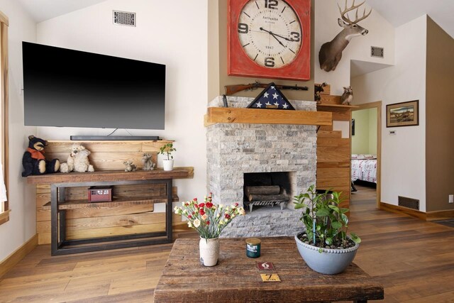 2144 N Jacobson Rd, Suttons Bay, MI 49682 - living area with a stone fireplace, wood finished floors, baseboards, and lofted ceiling