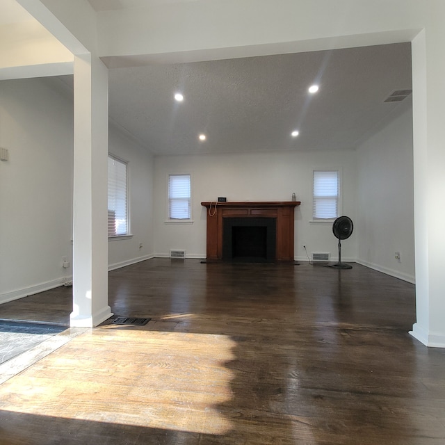 unfurnished living room featuring dark hardwood / wood-style flooring and a textured ceiling