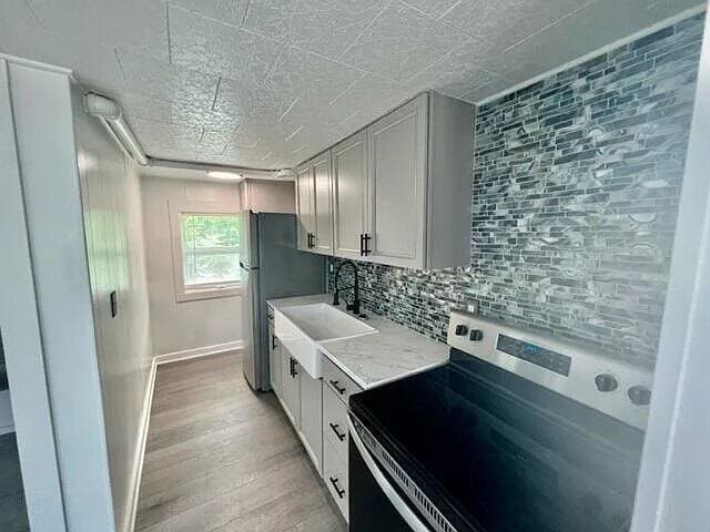 kitchen featuring range with electric cooktop, sink, white cabinetry, backsplash, and light hardwood / wood-style floors