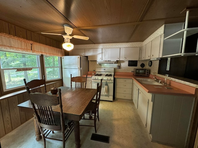 kitchen with ceiling fan, sink, wood walls, white appliances, and decorative backsplash