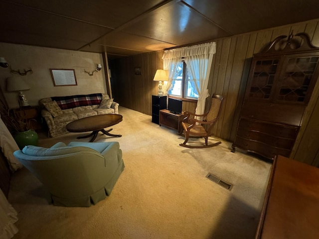 carpeted living room featuring wood walls