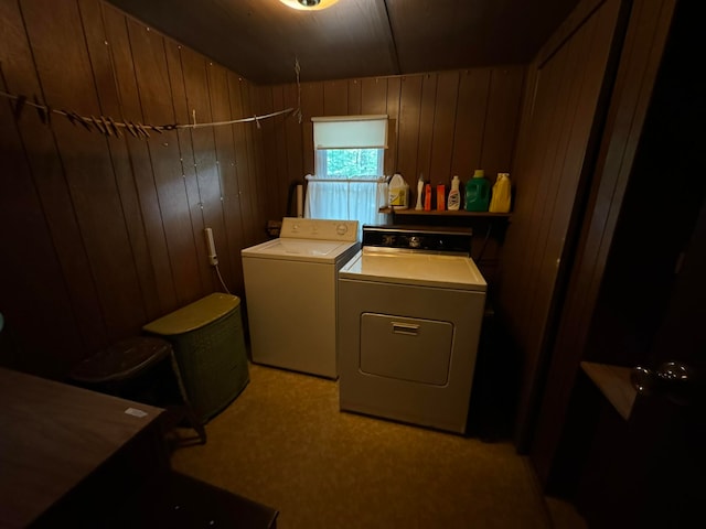 laundry room with washing machine and dryer, light colored carpet, and wood walls