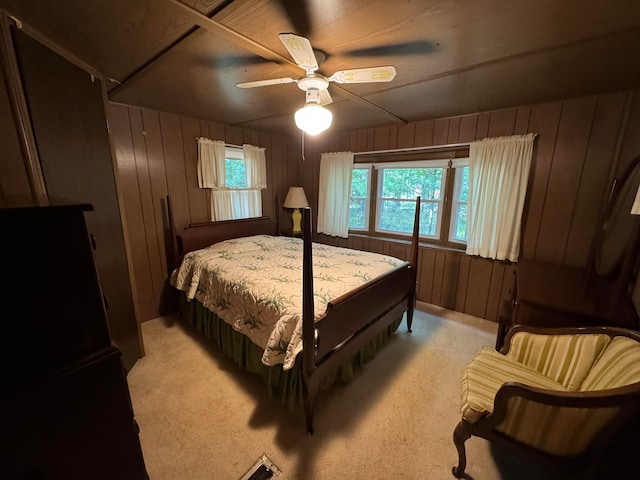 bedroom featuring ceiling fan, wood walls, and light colored carpet