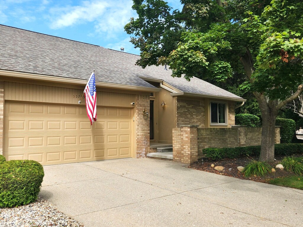 55799 Shelby Rd, Shelby Twp, MI 48316 - view of front of property featuring driveway, brick siding, a shingled roof, and a garage