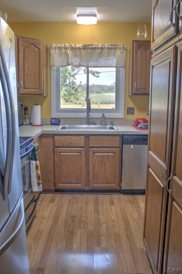 kitchen with appliances with stainless steel finishes, light hardwood / wood-style flooring, and sink