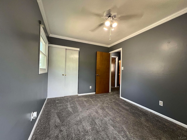 unfurnished bedroom with ceiling fan, a closet, ornamental molding, and dark colored carpet