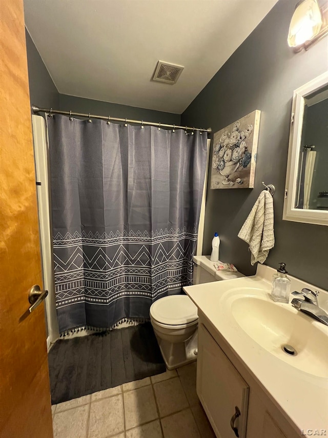 bathroom featuring toilet, vanity, tile patterned floors, and walk in shower