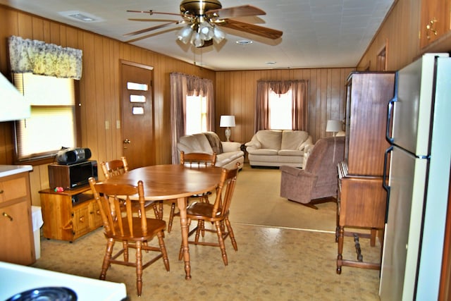 dining room featuring wood walls, plenty of natural light, and ceiling fan