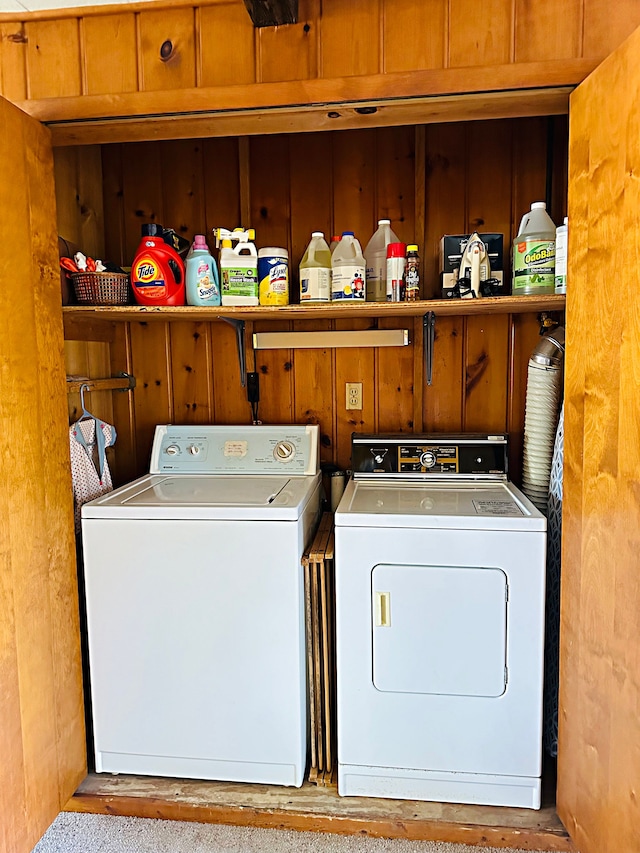 washroom featuring washer and clothes dryer and wood walls