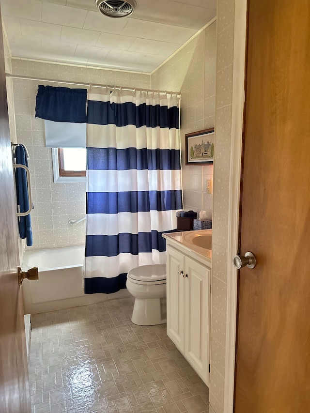 full bathroom featuring vanity, toilet, tile walls, and shower / bath combo with shower curtain