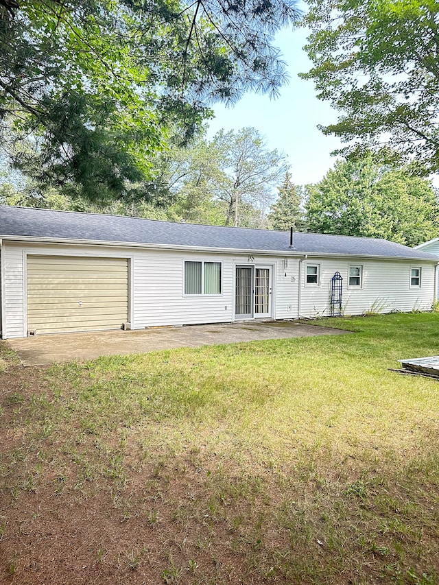 back of property featuring a lawn and a garage