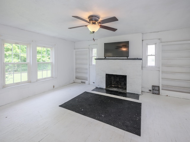 unfurnished living room featuring a fireplace, light hardwood / wood-style flooring, plenty of natural light, and ceiling fan