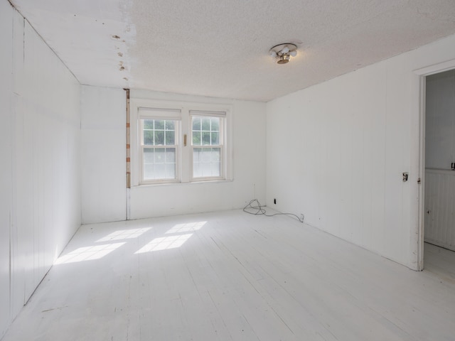 spare room with a textured ceiling and light hardwood / wood-style flooring