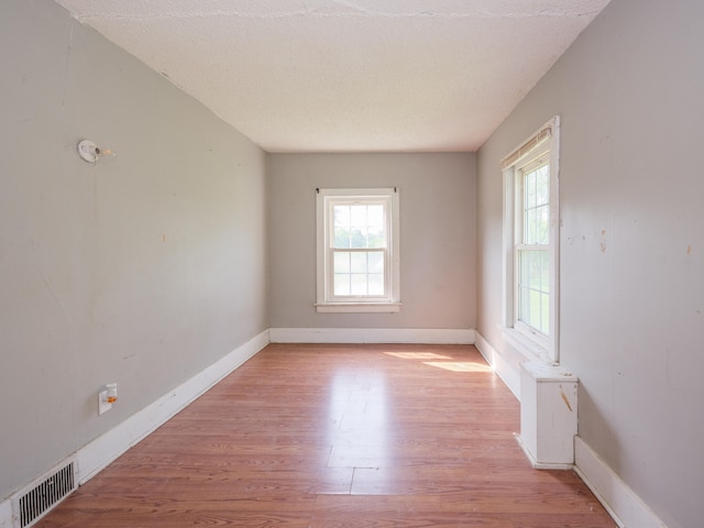 spare room featuring a textured ceiling and light wood-type flooring