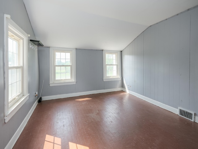 empty room featuring dark wood-type flooring, a healthy amount of sunlight, and vaulted ceiling