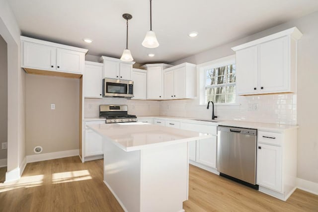 kitchen featuring white cabinetry, stainless steel appliances, a center island, pendant lighting, and sink