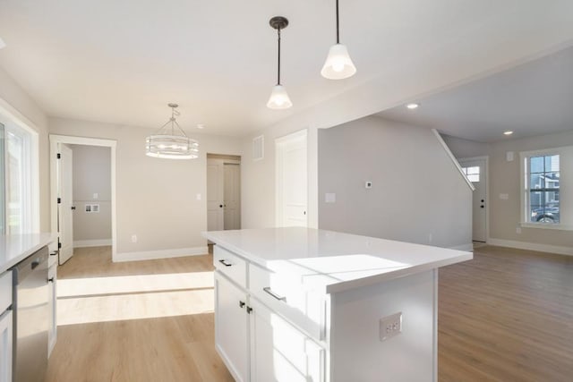 kitchen with dishwasher, pendant lighting, a center island, white cabinetry, and light hardwood / wood-style flooring