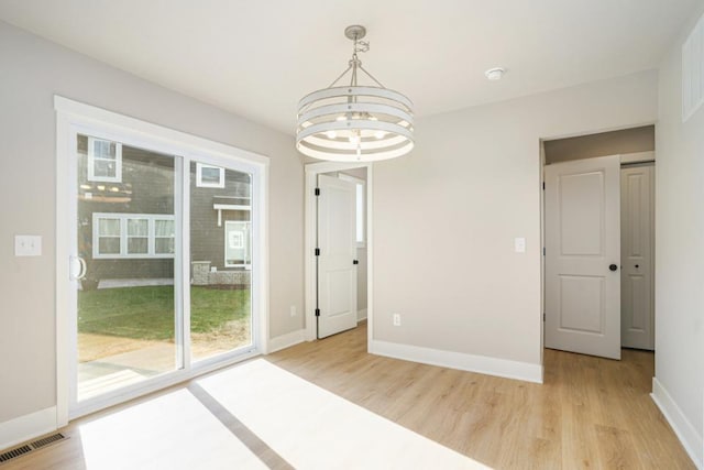 empty room featuring light hardwood / wood-style floors and a notable chandelier