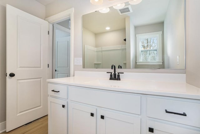 bathroom featuring hardwood / wood-style flooring, walk in shower, and vanity