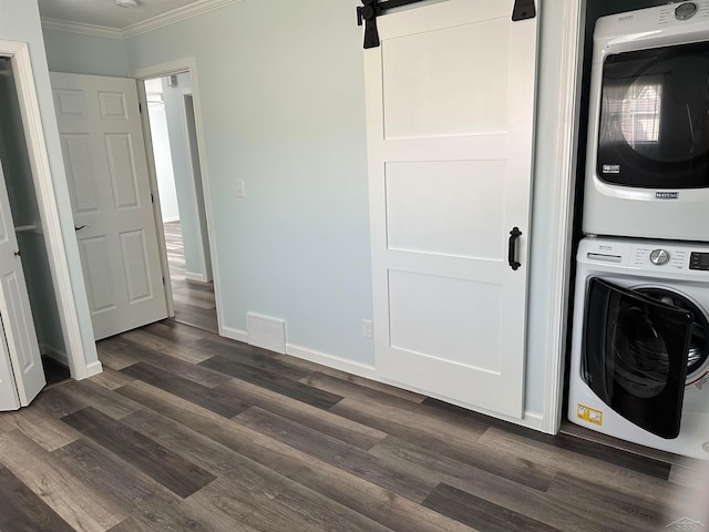 laundry room with dark hardwood / wood-style floors, a barn door, crown molding, and stacked washer and clothes dryer