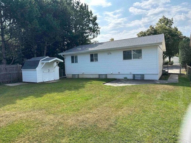 back of house with a yard, cooling unit, and a storage shed