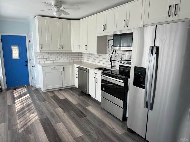 kitchen with appliances with stainless steel finishes, dark hardwood / wood-style flooring, backsplash, sink, and white cabinetry