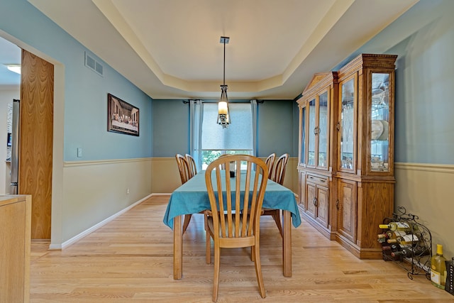 dining room featuring a raised ceiling and light hardwood / wood-style flooring