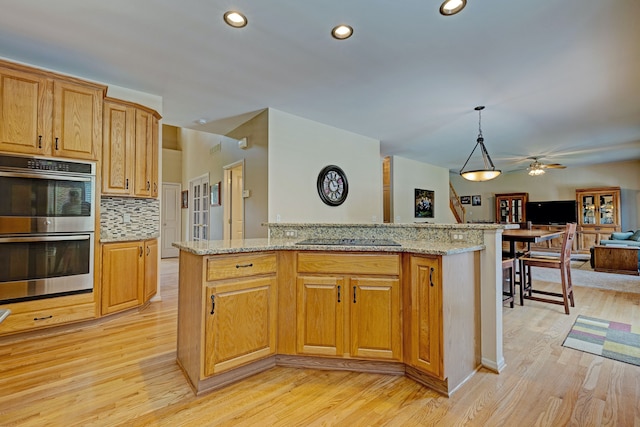 kitchen featuring pendant lighting, a center island, black electric cooktop, light hardwood / wood-style floors, and stainless steel double oven