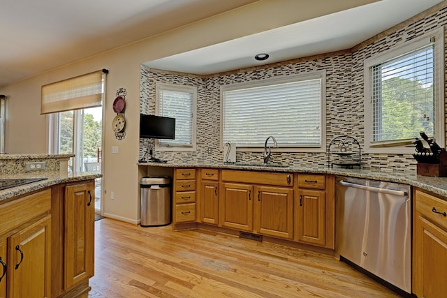 kitchen with light hardwood / wood-style flooring, stainless steel dishwasher, a wealth of natural light, and sink