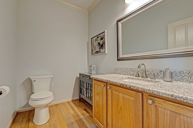 bathroom with wood-type flooring, vanity, toilet, and crown molding