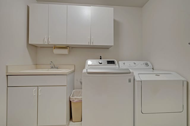 washroom with cabinets, washing machine and dryer, and sink