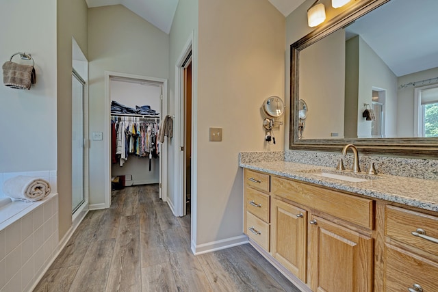 bathroom featuring hardwood / wood-style flooring, vanity, lofted ceiling, and independent shower and bath