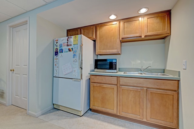 kitchen with white refrigerator, light tile patterned floors, and sink