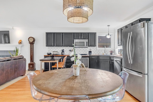 kitchen featuring sink, decorative light fixtures, light wood-type flooring, stainless steel appliances, and decorative backsplash