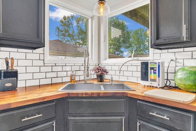 kitchen with wood counters, sink, backsplash, and hanging light fixtures