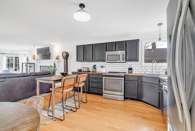 kitchen featuring stainless steel appliances, tasteful backsplash, light hardwood / wood-style floors, and decorative light fixtures