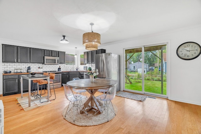 dining area with ornamental molding and light wood-type flooring