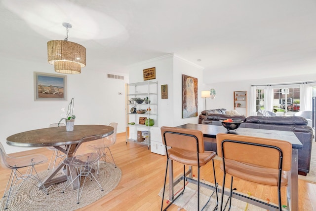 dining space featuring a notable chandelier, ornamental molding, and light wood-type flooring