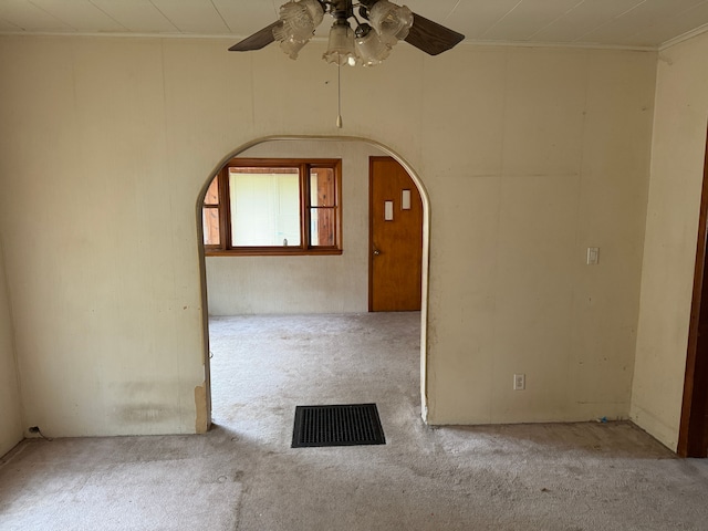 carpeted empty room featuring ceiling fan and crown molding