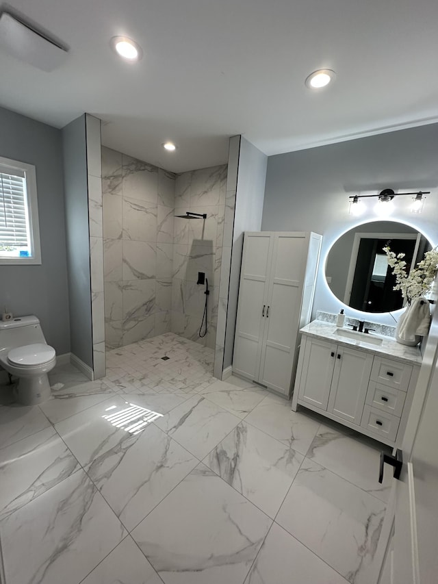 bathroom with a tile shower, vanity, and toilet