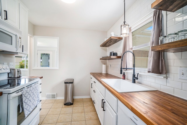 kitchen with butcher block countertops, pendant lighting, white cabinetry, and stainless steel stove