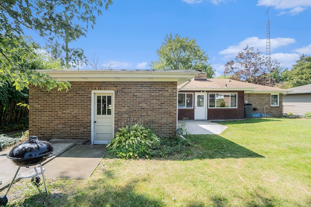 rear view of property featuring a yard, a patio, central AC, and an outdoor fire pit